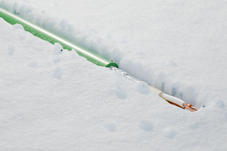 3D-Rendering: Dreiviertelansicht des abgesetzten Endes – Profinet-Kabel mit grünem Mantel, Geflecht- und Folienschirm und vier verseilten Adern in Weiß, Gelb, Blau und Orange, im Tageslicht im Schnee, Aufdruck „Cable Creations“